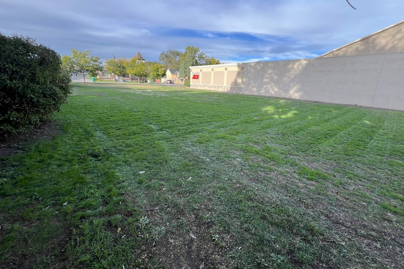 The open grass lot at 26 E Main St in Lehi, looking across the lawn toward Main Street.